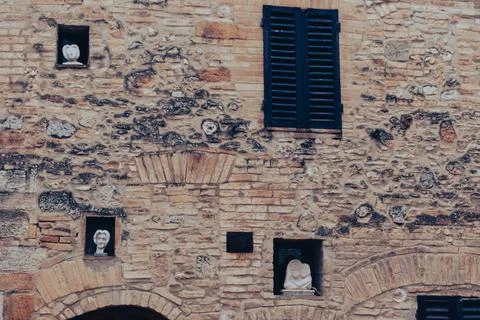 Ancient brick wall with statues on the facade Stock Photos