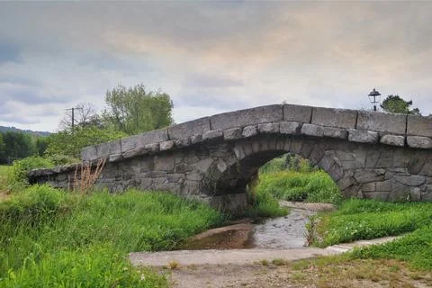 Ancient bridge built in stone over a small river Stock Photos