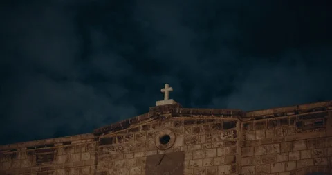 Ancient catholic church with cross on top and dark blue clouds moving at nigh Stock Footage 123712455