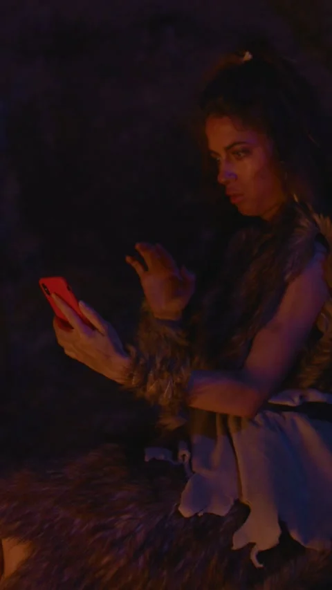 An ancient character uses modern technology in a primitive setting, creating a Stock Footage 310815027