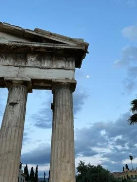 Ancient classical stone columns against blue sky with clouds and moon Foto stock