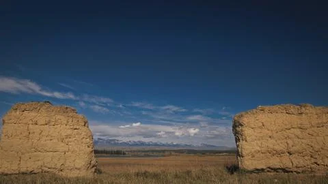 Ancient clay columns the backdrop of snow-capped mountains and clouds. Remains Stock Photos