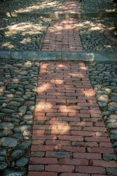 An ancient cobblestone path with a pattern of stones and bricks leads Stock Photos