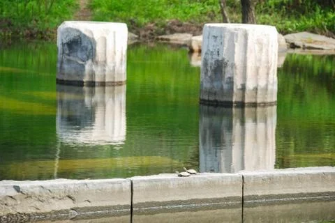 Ancient columns with reflection in the water at archeological site area. Stock Photos