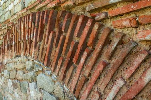 Ancient diagonal brick pattern embedded in historic masonry wall with weath.. Фото
