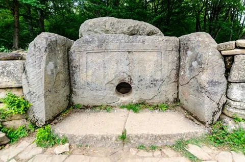 Ancient dolmen with circular opening in forest setting Stock Photos