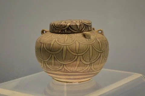Ancient earthenware jar in a museum with simple circular patterns drawn on it fr Stock Photos