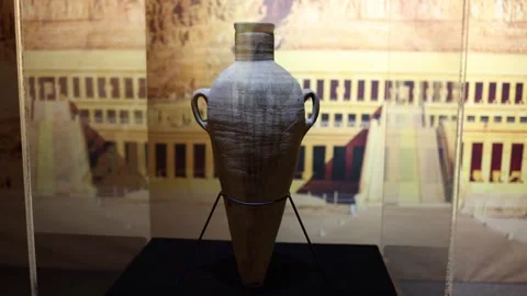 An ancient Egyptian amphora displayed in a museum, set against a backdrop of his Stock Footage 301792995
