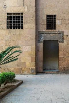 Ancient external old decorated bricks stone wall with windows and opened door Stock-Fotos