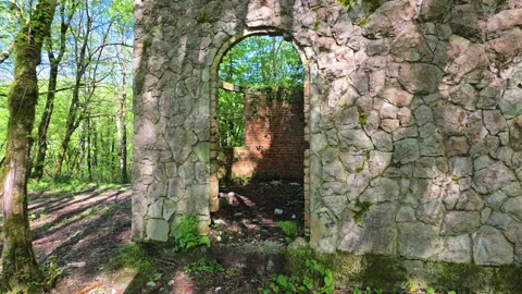 Ancient grotto ruins featuring a stone wall and an arched brick entrance leading Stock Footage 336170730