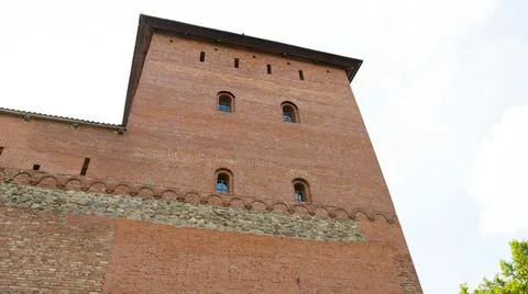 An ancient large castle tower with small red brick windows. Historic building of Foto stock
