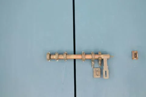 Ancient long rusty latch on blue gray closed door. Stock Photos