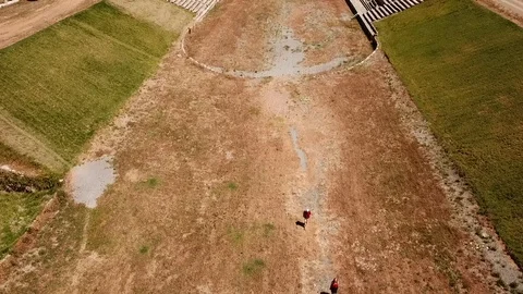 Ancient Messini - drone flight over stadium while tourists walk inside it Stock Footage 113426644