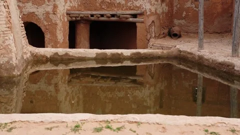 Ancient mud brick water basin with reflection in courtyard 動画素材 347973304