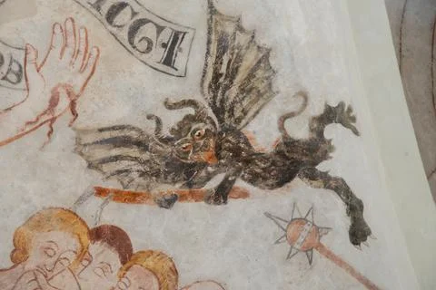 An ancient mural of a black devil with bat wings hacking at people Stock Photos