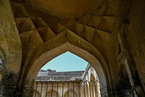 Ancient pointed stone arch with weathered vaulted ceiling inside historic f.. Stock Photos