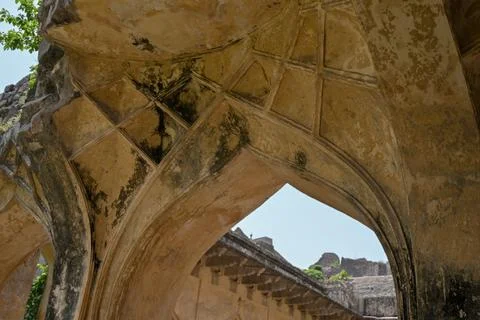 Ancient pointed stone arch with weathered vaulted ceiling inside historic f.. Stock Photos