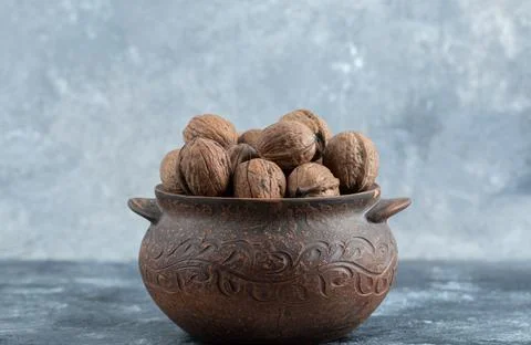 An ancient pot full of healthy walnuts on a gray background Stock Photos