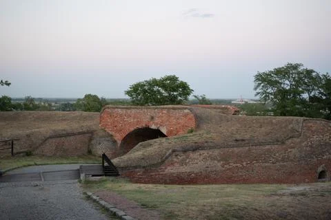 Ancient red brick fortification wall with an arched tunnel stands Stock Photos