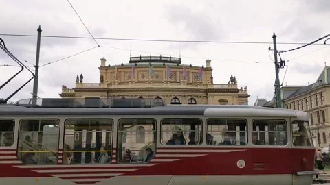 Ancient red tram moving in front of building with Socha Antonína Dvořáka Stock Footage 168737493