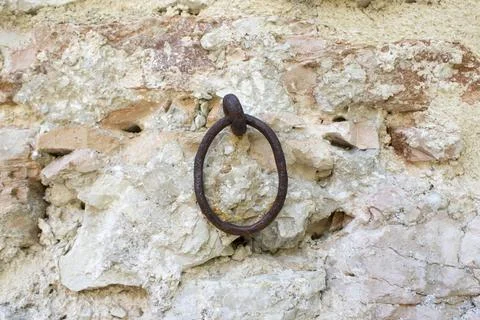 Ancient rough stone wall with an iron ring used to tie horses and cattle Stock Photos