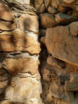 Ancient rough stone wall texture background close up with natural light Stock Photos