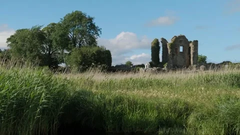 Ancient ruins surrounded by lush greenery near a calm waterway Stockbeeldmateriaal 306394151