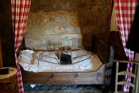 Ancient rustic bedroom interior with antique wooden bed heating system and .. Stock Photos
