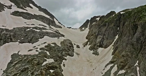 Ancient snow glacier among high mountains. The peaks of the mountains are Stock Footage 302098321