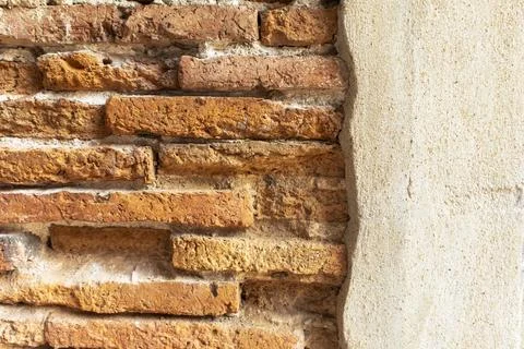 An ancient square stone wall with light brown plaster. Stock Photos