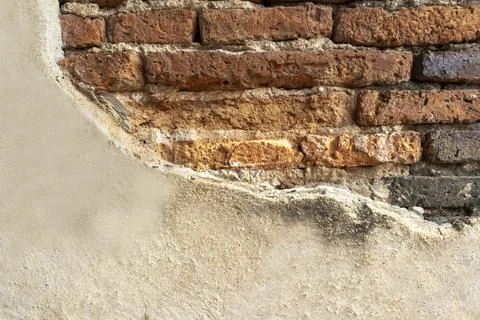 An ancient square stone wall with light brown plaster. Stock Photos