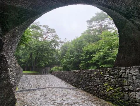 Ancient stone archway frames misty forest path Stock Photos