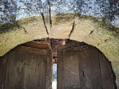 Ancient stone archway framing a rustic wooden gate in historic Spanish arch.. Stock-Fotos