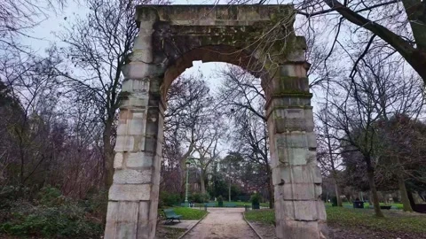 Ancient stone archway in Parc Monceau surrounded by nature, Paris, France Stockbeeldmateriaal 304147423