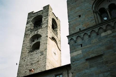 Ancient stone bell tower with a clock in Bergamo. Italy Stock Photos