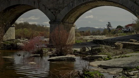 Ancient stone bridge arches crossing a low river Stock Footage 335461879
