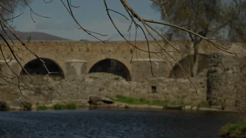 Ancient stone bridge with arches spanning a tranquil river Stock Footage 335461266