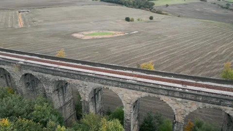 Ancient stone bridge spans autumn fields Stock-Footage 343872267