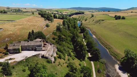 Ancient stone building nestles beside a winding river. Yorkshire Dales,  Ri.. Stock Footage 346284907