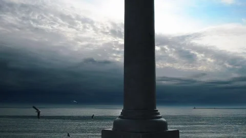 Ancient stone column silhouette against a dramatic stormy ocean sky at sunset Video stock 344041193