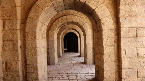 Ancient stone corridor with repeating arches illuminated by warm natural light, Stock-Fotos