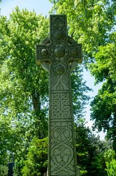 Ancient Stone Cross with Celtic Patterns in a Lush Green Forest Stock Photos