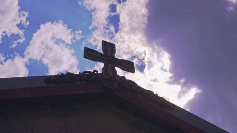 Ancient stone cross on an old stone building against the backdrop of flying clou Stock Footage 102725648