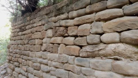 Ancient Stone Masonry Wall Featuring Embedded Weathered Wooden Structural Beams Foto stock