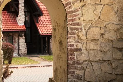 An ancient stone passage frames a picturesque view of a rustic dwelling featu 写真素材