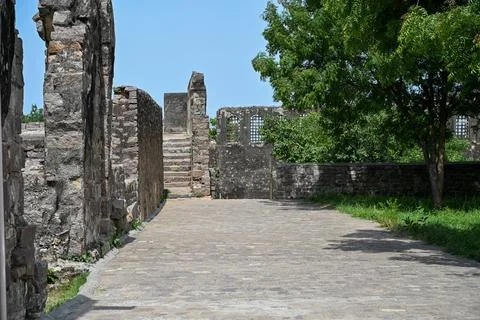 Ancient Stone Pathway Leading Through Historic Fort Ruins Under Green Trees Фото