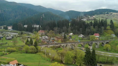 An ancient stone railway bridge over a fast-flowing river and a road among the Video stock 107971628