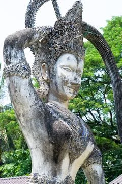 Ancient stone statue touching its ornate headdress in buddha park, vientiane Stock Photos