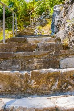 Ancient stone steps climbing a hillside path with metal railing and surroun.. Stock Photos