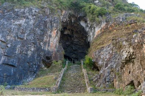 Ancient stone steps lead into a dark cave entrance Stock Photos